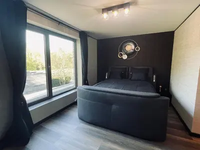 a bedroom with a large bed and a large window at Tranquilo Maaseik in Maaseik