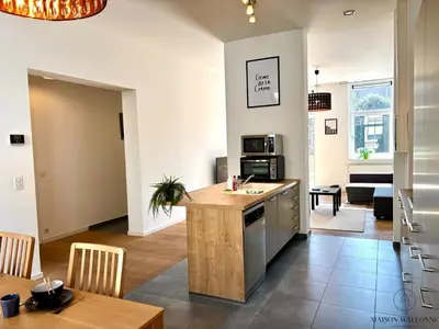 a kitchen and living room with a counter and a table at Le Botanique des Augustins -100m2 en plein centre in Liège
