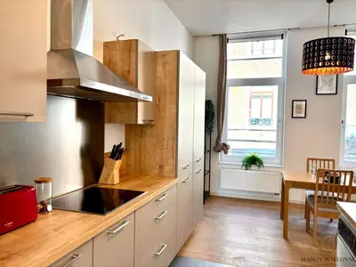a kitchen with white cabinets and a table and a window at Le Botanique des Augustins -100m2 en plein centre in Liège