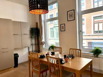 a dining room with a table and chairs and a kitchen at Le Botanique des Augustins -100m2 en plein centre in Liège