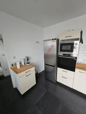 a kitchen with a stainless steel refrigerator and a microwave at appartement ouvert sur une pièce in Liège