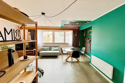 a living room with a table and a green wall at Le parfait Studio de la Cité Ardente - Central in Liège