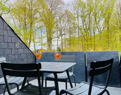 a table and chairs on a balcony with two drinks at La réserve by la Villa KerKus in Fraipont