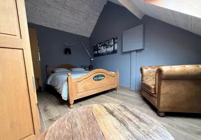 a bedroom with a bed and a chair at La réserve by la Villa KerKus in Fraipont