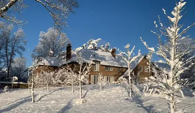 a house covered in snow with trees in the foreground at La réserve by la Villa KerKus in Fraipont