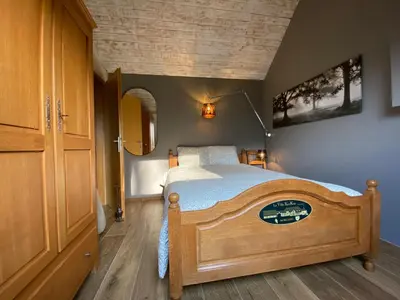 a bedroom with a wooden bed with a wooden floor at La réserve by la Villa KerKus in Fraipont