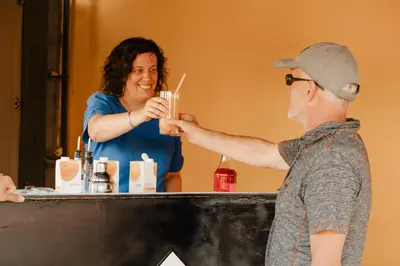 a woman serving a man a drink at a bar at Alivio - Thuiskomen bij jezelf op vakantie in Lummen