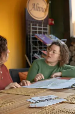 two women sitting at a table looking at a book at Alivio - Thuiskomen bij jezelf op vakantie in Lummen