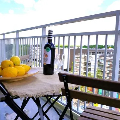 a bottle of wine and a plate of fruit on a table on a balcony at Stijlvol App in Genk Centrum in Genk