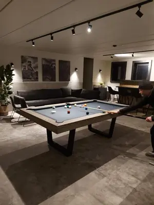 a man standing in a living room with a pool table at Het Maashuis in Maasmechelen