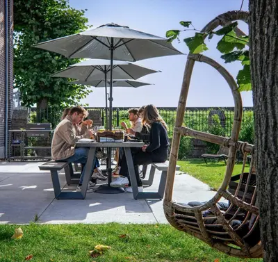 a group of people sitting at a table under an umbrella at Het Maashuis in Maasmechelen