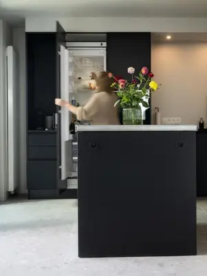 a man in a kitchen with an open refrigerator at Het Maashuis in Maasmechelen