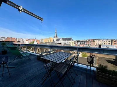 a wooden deck with chairs and a table on a balcony at Le Panoramique des Carmes - Vue Cathédrale in Liège