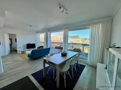 a living room with a table and a large window at Le Panoramique des Carmes - Vue Cathédrale in Liège