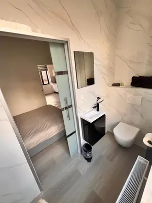 a bathroom with a bed and a sink and a toilet at FourSuites Liège in Liège