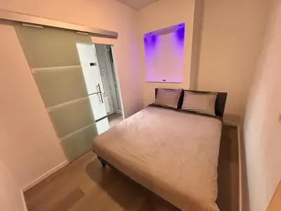 a small bedroom with a bed with a purple window at FourSuites Liège in Liège