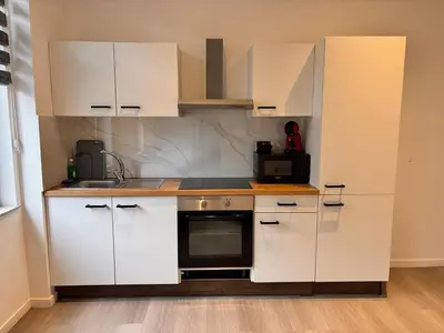 a small kitchen with white cabinets and a microwave at FourSuites Liège in Liège