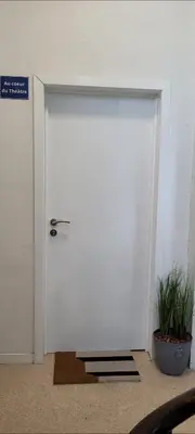 a white door in a room with two plants at Au coeur du théâtre in Verviers