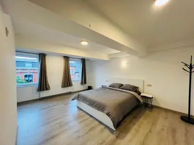 a bedroom with a large bed and two windows at Maison d’Ans in Ans