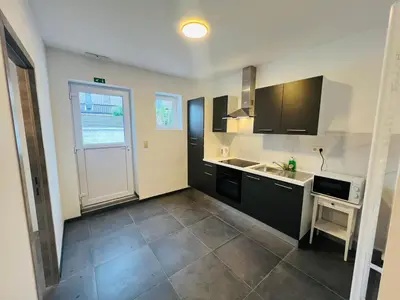 a kitchen with black and white cabinets and a sink at Maison d’Ans in Ans