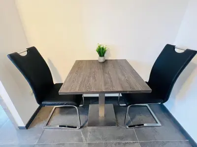 a wooden table with two chairs and a vase on it at Maison d’Ans in Ans