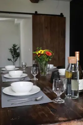 a wooden table with plates and glasses and a bottle of wine at Maas & Me in Dilsen-Stokkem