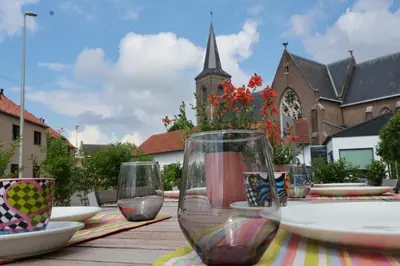 a table with wine glasses on a table with a church at Maas & Me in Dilsen-Stokkem