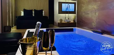a hot tub with a bottle of wine in a bedroom at Home Sweet House in Hermée