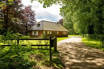 a house on the side of a road with a fence at Tussen Heide en Bos in het Nationaal Park Hoge Kempen in Oudsbergen