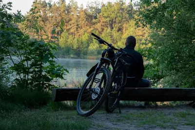 a man sitting on a bench with a bike at Tussen Heide en Bos in het Nationaal Park Hoge Kempen in Oudsbergen