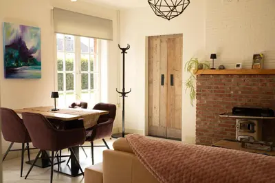 a dining room with a table and a brick wall at Tussen Heide en Bos in het Nationaal Park Hoge Kempen in Oudsbergen