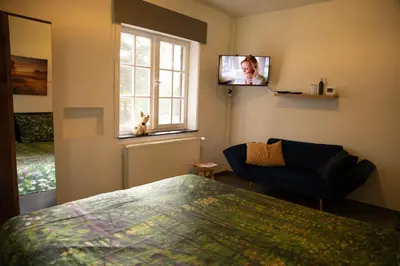 a bedroom with a bed and a tv on the wall at Tussen Heide en Bos in het Nationaal Park Hoge Kempen in Oudsbergen
