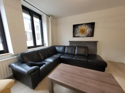 a living room with a black leather couch and a table at Biesenbilzen in Bilzen