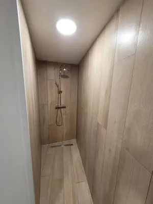 a bathroom with a shower with wooden walls at Biesenbilzen in Bilzen