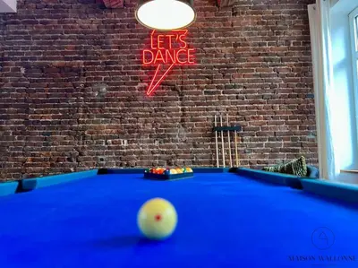 a pool table in front of a brick wall with a sign at Grande Maison au cœur du Carré - Quartier Festif! in Liège