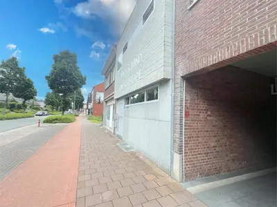 a brick building with a sidewalk next to a street at t Vennehuisje in Genk