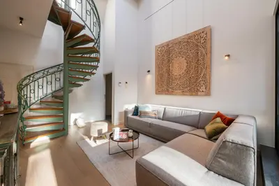 a living room with a couch and a spiral staircase at De Droomhoeve in Bilzen