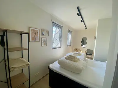 a bedroom with a bed with white sheets and towels at Skylodgenk in Genk