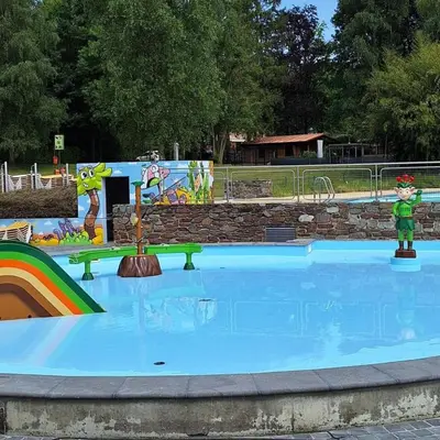 a large swimming pool with a rainbow in a park at Infinity met hottub op Jocomo Park in Lanaken