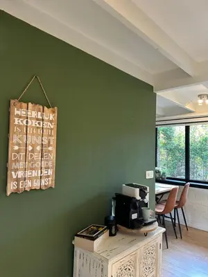 a room with a green wall with a microwave on a table at Vakantiehuis Lanaken in Lanaken