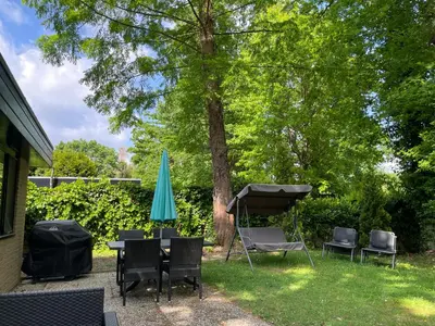 a patio with a table and a blue umbrella and chairs at Vakantiehuis Lanaken in Lanaken