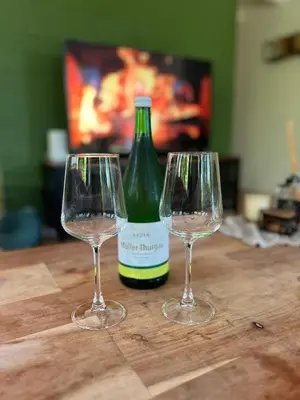 two wine glasses on a wooden table with a bottle of wine at Vakantiehuis Lanaken in Lanaken
