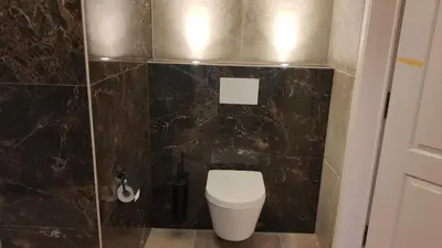 a bathroom with a toilet and a black tiled wall at Villa kleinwellness in Lanaken