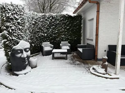 a yard covered in snow with a bench and a hedge at Villa kleinwellness in Lanaken