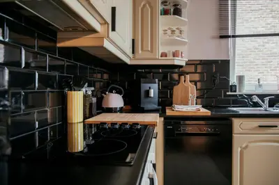 a kitchen with black tiled walls and a stove at La Courte Échelle in Verviers