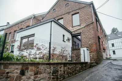 a brick building with a fence on the side of it at La Courte Échelle in Verviers