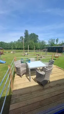 a deck with a table and chairs and a playground at Puck B&B Babbita in Hasselt