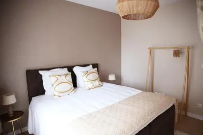 a bedroom with a bed with white sheets and gold pillows at Le 118 Guillemins, avec Parking in Liège