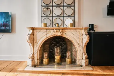 a stone fireplace in a living room with a table at Urbanchic Appartement élégance hyper centre in Liège