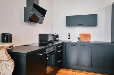 a kitchen with black cabinets and a sink and a microwave at Urbanchic Appartement élégance hyper centre in Liège